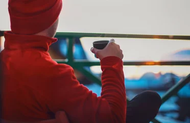 Foto op Canvas Man in winter clothing drinking hot herbal tea. Winter evening from a beautiful balcony in the suset time on Baikal Lake. © Dasha Petrenko