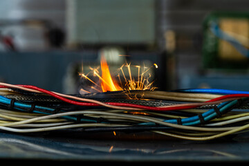 Flames, sparks, smoke between electrical cables, closeup. Short circuit in the twisted wires from the electrical devices, fire hazard concept - 788711866