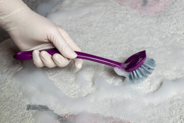 Blue brush on the floor with hand in rubber glove. Cleaning.