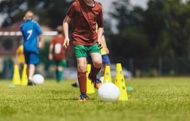 Physical Outdoor Activities for Kids. Boys Play Balls At Soccer Training Drill. Children Running at Practice Field. Elementary-Age Children at Slalom Training Drill