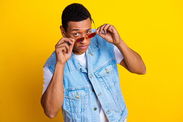 Photo of cool flirty confident guy dressed jeans waistcoat touching glasses looking at you isolated on vibrant yellow color background - obrazy, fototapety, plakaty
