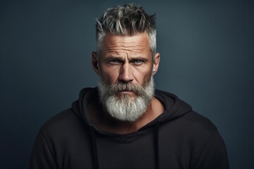 Despise. Angry and grumy Caucasian gray-haired bearded man sulking, furrow eyebrows and staring with anger and contempt, boiling from furious emotions, standing over grey background - obrazy, fototapety, plakaty