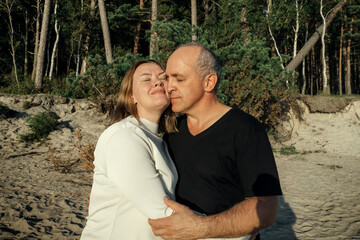 A man and a woman hug each other warmly on a sandy beach.