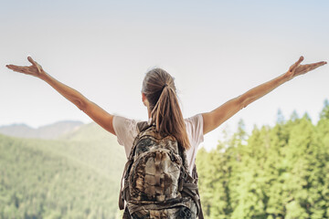 Happy Hiker Traveler female embracing life and enjoying freedom with open arms over sky and...