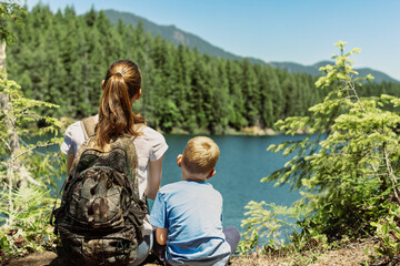 parent and child sitting in forest nature setting, summer family travel concept 