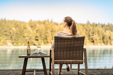 young woman enjoying a peaceful summer holiday in nature relaxing with glass of wine and book 