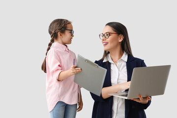 Little girl with clipboard and her working mother on light background