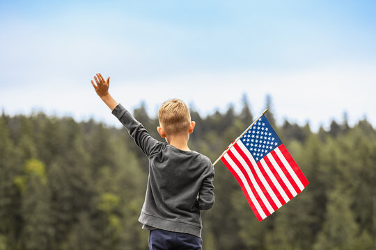 Happy boy holding American USA flag outdoors, people patriotism, 4th of July concept. 