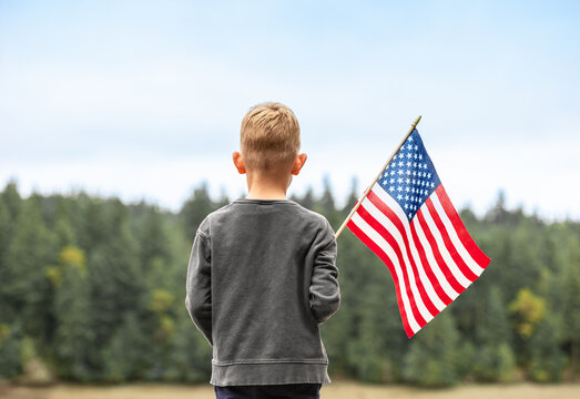 Child holding American USA flag outdoors, people patriotism, 4th of July concept. 