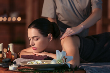 Young woman getting massage in dark spa salon, closeup