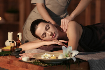 Obraz na płótnie Canvas Young woman getting massage in dark spa salon, closeup