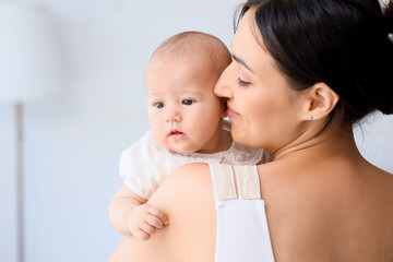 Happy mother with cute little baby in room at home