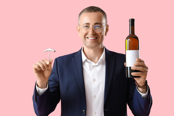 Mature man with bottle of wine and opener on pink background