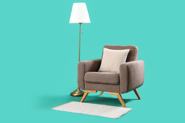 Cozy armchair with standard lamp on turquoise background