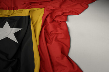 waving national flag of east timor on a gray background.