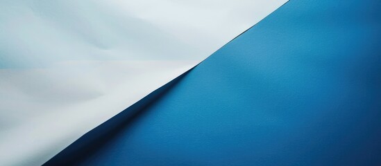 Two-toned paper in blue and white lies overlapped on the floor, dividing the background image in half.