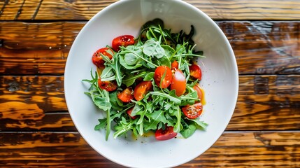 A dish of salad with tomatoes and greens on a wooden table