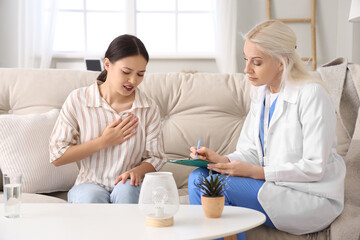 Obraz premium Ill young Asian woman with doctor at home