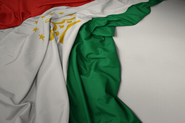waving national flag of tajikistan on a gray background.