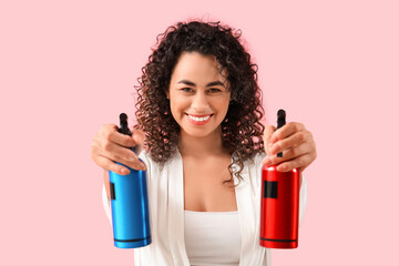 Beautiful African-American woman with hair sprays on pink background