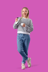 Pretty young woman pouring espresso from geyser coffee maker into cup on purple background