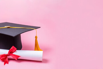 Graduationshut und Zeugnis vor rosa Hintergrund 