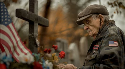 Fotobehang An elderly veteran standing solemnly by a decorated cross in a cemetery, his hand resting on the American flag, lost in silent remembrance. © Maksym