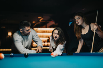 A group of friends focused on winning at pool in a casual, ambient setting.