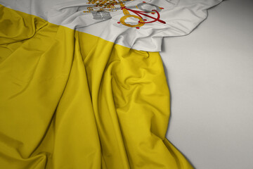 waving national flag of vatican city on a gray background.