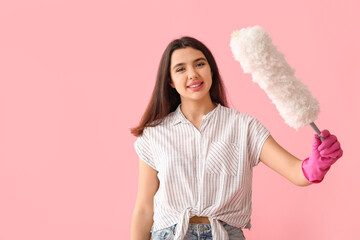 Young woman in rubber gloves with pp-duster on pink background