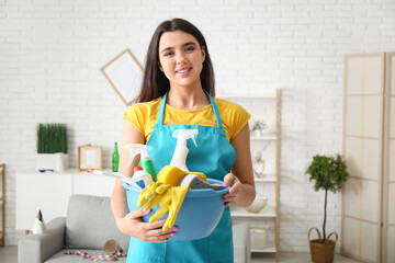 Young woman with sponge and cleaning supplies in living room