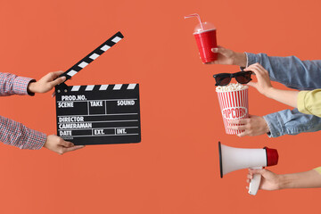 Many hands with bucket of popcorn, movie clapper and megaphone on orange background