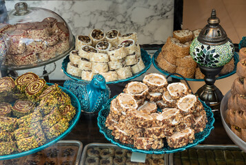 Turkish sweets in a bake shop window. Looking through the glass at blue plates piled with assorted...
