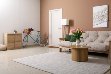 Interior of living room with sofa, bicycle, coffee table and flowers