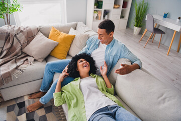 Top view photo of cute excited couple dressed casual outfits having rest couch talking indoors...