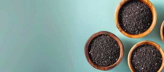 Organic black sesame placed in wooden bowls against a pastel background, conveying a health-oriented concept. Shot from above with space for text.