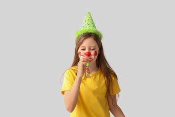 Funny girl with clown makeup, party hat and whistle on white background. April Fool's Day celebration