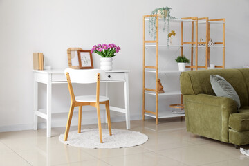 Vase with tulips on table in light living room interior