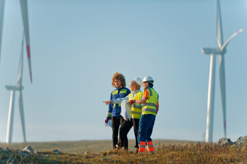 A team of engineers and workers oversees a wind turbine project at a modern wind farm, working together to ensure the efficient generation of renewable energy - obrazy, fototapety, plakaty