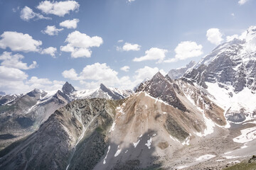 Panoramic landscape in the mountains with rocks and scree, with grass glades, snow and glaciers on...