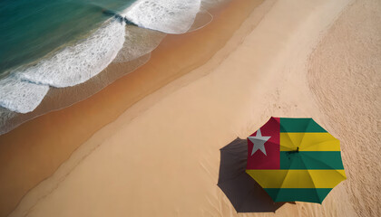 An aerial vista of a sandy beach with gentle ocean waves, featuring a beach umbrella adorned with the Togo flag. Ideal for Togo tourists seeking seaside relaxation