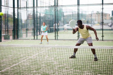Portrait of emotional man paddle tennis player during friendly doubles pair match with woman partner at outdoors court