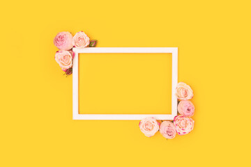 Border frame made of pink rose flowers on a yellow background. Cute festive floral concept.