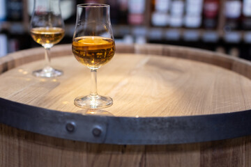 Whisky glass close-up on oak barrel on blurred colorful background