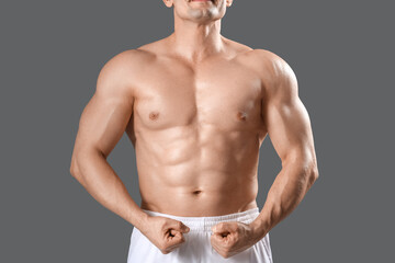 Muscular male bodybuilder showing muscles on grey background