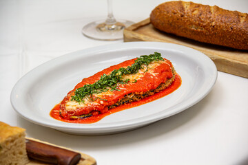 Filete de pescado empanizado con salsa de tomate en plato blanco.