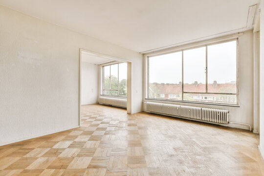 Spacious empty room with large windows and parquet floor