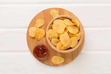 Appetizing potato chips on wooden background, top view