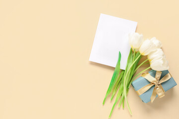 Blank card with beautiful white tulips and gift box on beige background. Mother's Day celebration