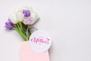 Greeting card with text HAPPY MOTHER'S DAY and beautiful tulips on white background